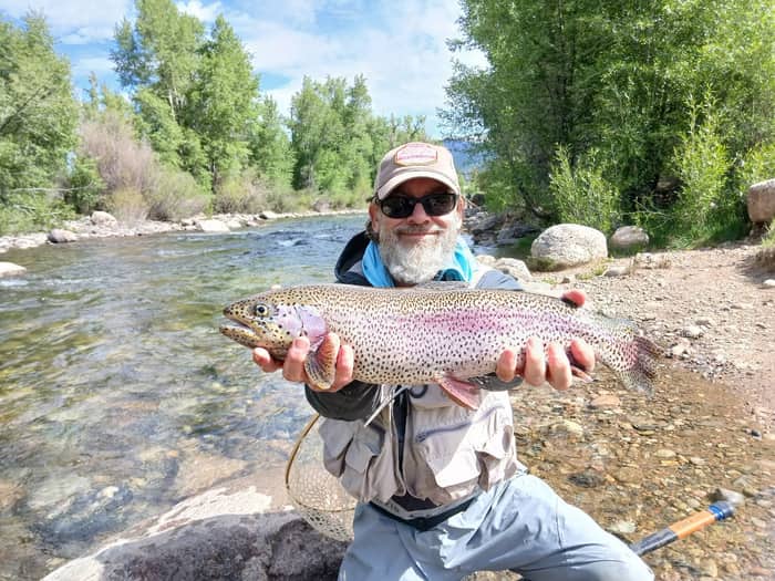 Angler holding a large rainbow trout on a summer river